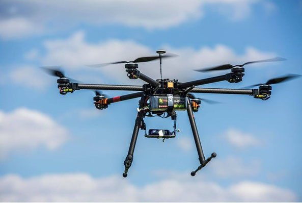 Hexacopter drone carrying a suspended payload package in flight